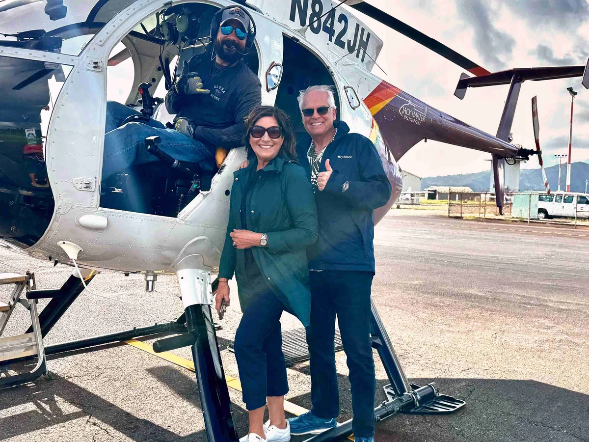 Dr. Peter Robbins and his wife by a helicopter in Kauai